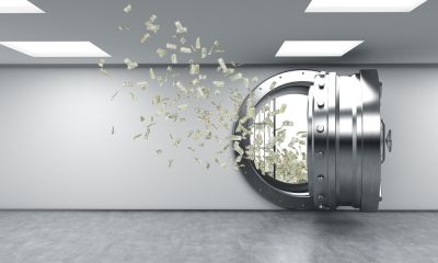money bills flying out of the open armoured bank cell door